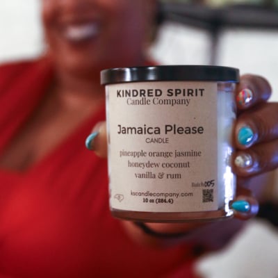 Monique Mackey of Kindred Spirit stands in front of a display of handcrafted candles and home goods at Boxyard RTP pop-up shop.